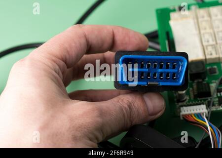 L'elettricista tiene in mano la spina OBD2 dello scanner per errori di diagnostica dell'auto. Foto Stock