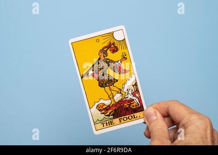 Mano che tiene la carta del tarocco del fool. Foto Stock