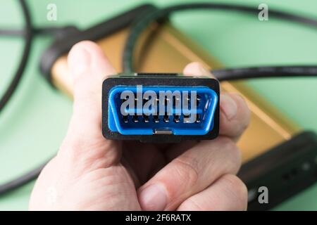 L'elettricista tiene in mani il computer errore diagnostico auto scanner OBD2 spina. Attrezzatura, interfaccia diagnostica. Assistenza, riparazione, manutenzione auto Foto Stock