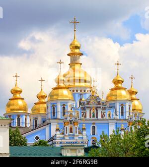 Cupole dorate della Cattedrale a cupola d'oro di San Michele a Kiev in primavera contro un cielo blu nuvoloso in una calda giornata di primavera. Foto Stock