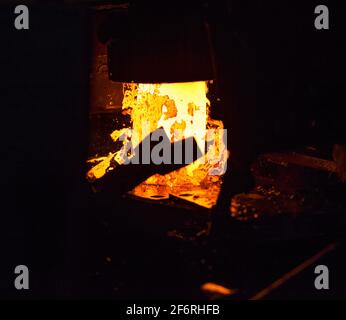 Macchina di pressatura (punzonatura). Parti cuscinetto pista esterna di produzione. Metallo rosso-caldo con strisce di scorie. Foto Stock