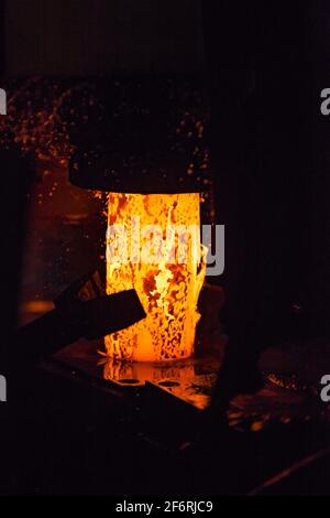 Macchina di pressatura (punzonatura). Parti cuscinetto pista esterna di produzione. Metallo rosso-caldo con scoria di ossido Foto Stock