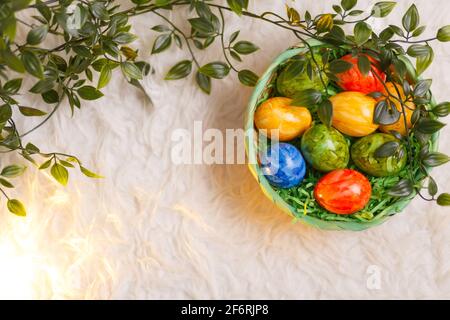 Carta di Pasqua. Composizione piatta con uova di pasqua in un cesto su sfondo bianco. Foto Stock