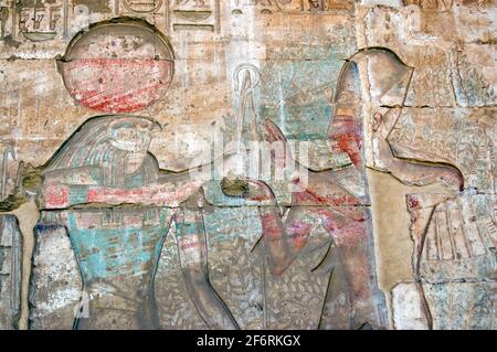 Un'antica scultura geroglifica egiziana che mostra il falco guidato da dio Horus con il faroah Ramses II prima dell'albero sacro della vita. Sculture giganti Foto Stock