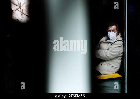 Donna sedette alla fermata dell'autobus guardando sospettosamente la vita sulla strada. Foto Stock