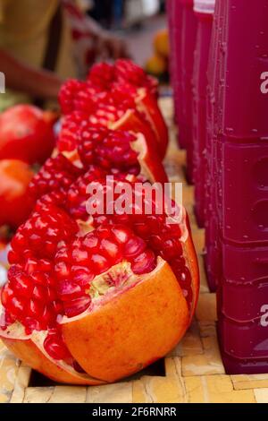 Bangkok, Thailandia - 16 luglio 2016: Melograni freschi accanto a bottiglie di succo di frutta fresco. Foto Stock