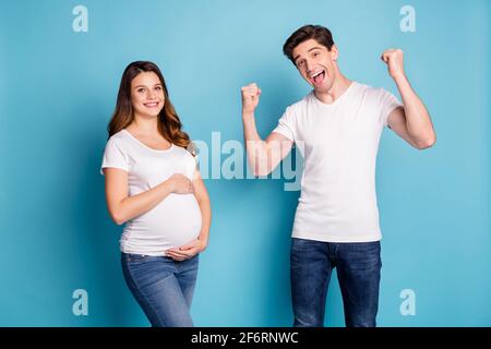 Ritratto fotografico di due persone marito mostrando muscoli in attesa ragazzo nato con la moglie incinta isolato sfondo di colore blu brillante Foto Stock