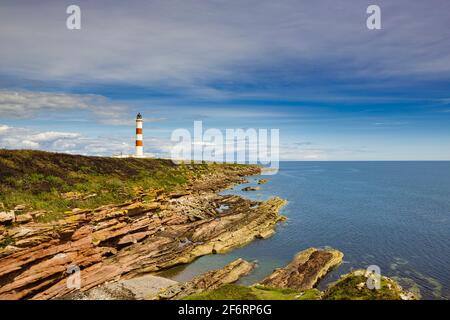 La costa rocciosa della penisola di Tarbat Ness con il faro in lontananza. Foto Stock