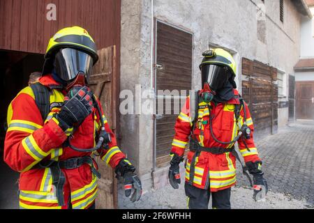 Wemding, Germania. 26 Marzo 2021. Due vigili del fuoco si trovano di fronte a un ex capanno con attrezzatura completa. Poiché non è possibile al momento svolgere alcuna formazione di protezione respiratoria a causa del coronavirus, i vigili del fuoco hanno costruito un percorso di ostacoli in un ex capanno in circa 200 ore di lavoro. Credit: Stefan Puchner/dpa/Alamy Live News Foto Stock