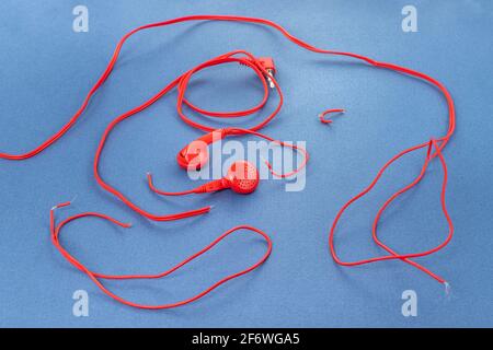 Cuffie su sfondo blu. Cuffie strappate. Riparazione dei dispositivi elettronici. Filo rotto. Foto Stock