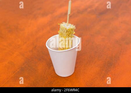 Una pannocchia gnawed di mais appena bollito in una tazza di carta sul tavolo. Concetto di fast food. Foto Stock