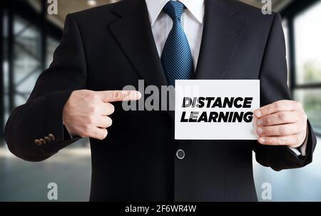 Uomo d'affari mostra una scheda con il messaggio di apprendimento a distanza. Concetto di e-learning o formazione online Foto Stock