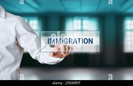 Mano dell'uomo premendo la parola immigrazione su una schermata di visualizzazione della ricerca virtuale. Domanda on line per l'immigrazione. Foto Stock
