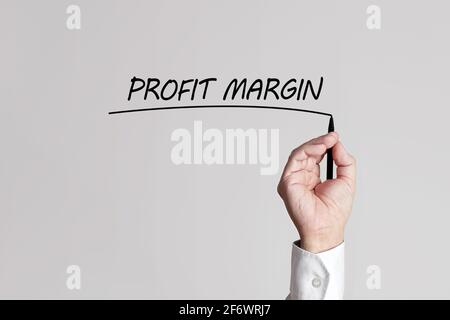 La mano di uomo d'affari con la penna sottolinea il margine di profitto di parole su uno schermo virtuale di sfondo grigio. Foto Stock