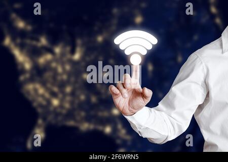 Uomo d'affari che preme l'icona della connessione Wi-Fi su uno schermo di visualizzazione virtuale. Concetto di connessione wireless WiFi globale. Foto Stock