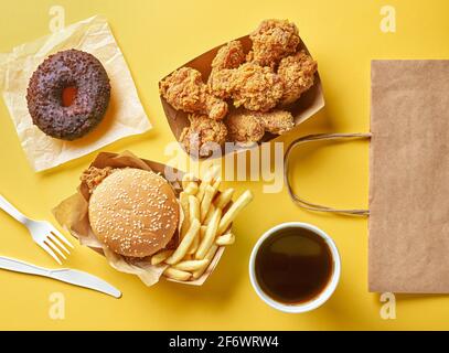 vari prodotti per fast food e borsa per la spesa in carta su sfondo giallo, vista dall'alto Foto Stock