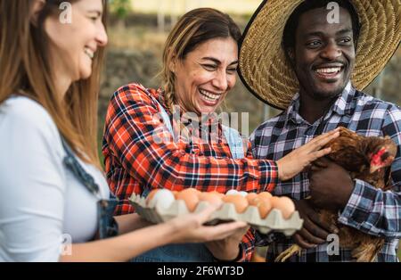 Felici coltivatori che raccolgono uova fresche nel giardino dell'henhouse - Concetto di stile di vita delle persone in fattoria Foto Stock