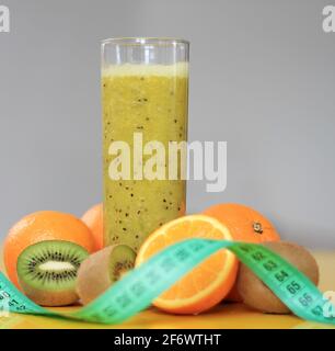 arancio appena spremuto con succo di frutta kiwi in un bicchiere con nastro adesivo su una foto da tavola Foto Stock