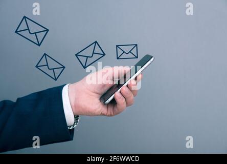 Un uomo d'affari che riceve molti nuovi messaggi, e-mail al telefono. Uomo che tiene il telefono. Immagine del concetto di business. Foto Stock