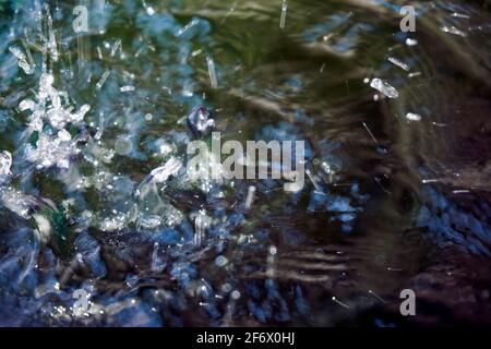 Grande puddle: La pioggia cade in un puddle e gocce d'acqua sulla superficie increspano Foto Stock