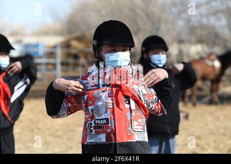 (210403) -- BURQIN, 3 aprile 2021 (Xinhua) -- Parasat Zhumabek, uno studente di grado senventesimo della Oymak Boarding School, si riscalda durante una classe equestre nella contea di Burqin, nella regione autonoma di Xinjiang Uygur, 30 marzo 2021. La gente nella regione autonoma di Xinjiang Uygur ha una tradizione di allevamento di cavalli e di equitazione. La scuola di imbarco di Oymak ha cominciato ad offrire le classi equestri alla fine del 2019. Gli studenti, la maggior parte dei quali provengono da famiglie di pastori, imparano sia la conoscenza teorica che la pratica di equitazione sulle classi equestri. Dopo le lezioni, gli studenti si rafforzano fisicamente e amano Foto Stock