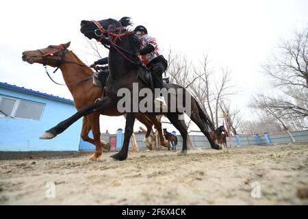 (210403) -- BURQIN, 3 aprile 2021 (Xinhua) -- gli studenti della scuola di imbarco di Oymak praticano l'equitazione durante una classe equestre nella contea di Burqin, nella regione autonoma di Xinjiang Uygur, nel nord-ovest della Cina, 29 marzo 2021. La gente nella regione autonoma di Xinjiang Uygur ha una tradizione di allevamento di cavalli e di equitazione. La scuola di imbarco di Oymak ha cominciato ad offrire le classi equestri alla fine del 2019. Gli studenti, la maggior parte dei quali provengono da famiglie di pastori, imparano sia la conoscenza teorica che la pratica di equitazione sulle classi equestri. Dopo le lezioni, gli studenti si rafforzano fisicamente e amano la vita e la natura più t Foto Stock