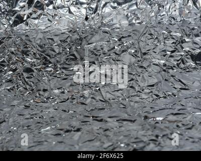 Foglio sottile di fondo foglia argentata con superficie lucida e irregolare Foto Stock