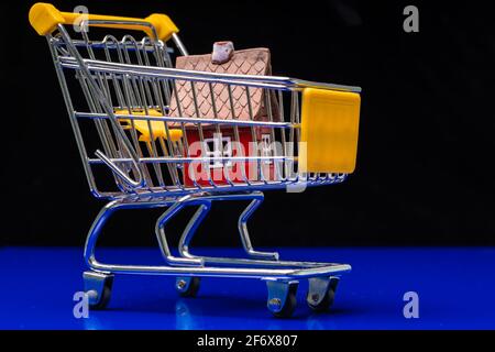 Casa rossa all'interno del carrello. Come diventare un proprietario di abitazione di prima volta. Concetti circa lo shopping in linea che i consumatori possono comprare le cose direttamente dalla loro sede. Foto di alta qualità Foto Stock