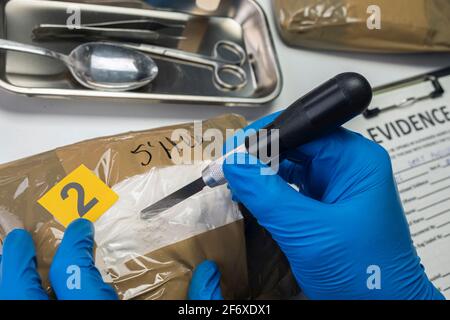 Polizia specializzata Open bundle di droga in laboratorio di criminalità, immagine concettuale Foto Stock