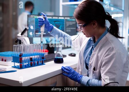 Scienziato che cerca micropipetta per test di biologia, malattie scientifiche, sanità. Donna ricerca un nuovo esperimento in laboratorio moderno, analizzando il lavoro farmaceutico con attrezzature moderne. Foto Stock