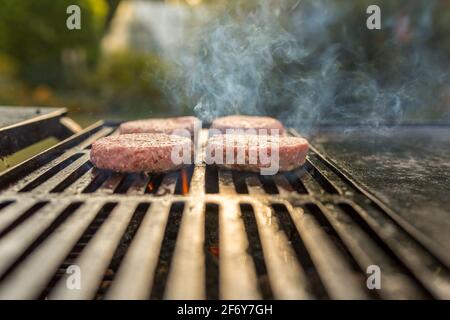 Hamburger che cucinano su fiamme alla griglia - concetto di svago, cibo e vacanze Foto Stock