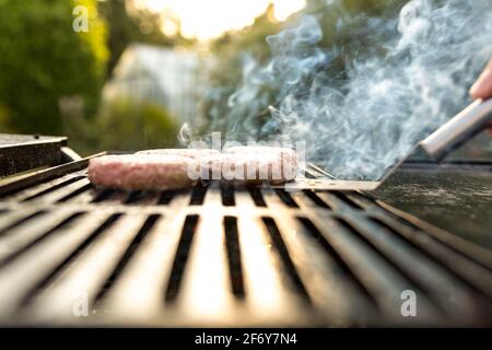 Hamburger che cucinano su fiamme alla griglia - concetto di svago, cibo e vacanze Foto Stock