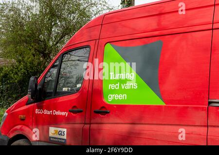 Pulmino rosso Parcelforce in tutto il mondo con uno slogan ecologico Turning Red Vans Green sul lato, Regno Unito Foto Stock
