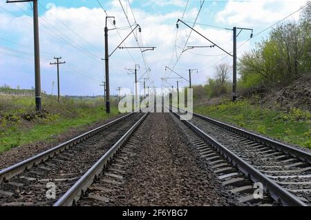 Vista panoramica di due ferrovie che passano dritto attraverso il campo verde. Orizzonte Foto Stock