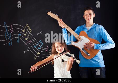 Fratello e sorella che suonano uno strumento musicale accanto a a. lavagna Foto Stock