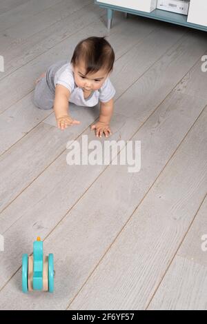 bambino di 8 mesi strisciando verso il giocattolo Foto Stock