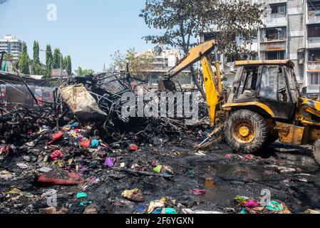 Mumbai , India - 30 marzo 2021, escavatori gommati che lavorano su macerie bruciate e metallo ritorto dal fuoco a Goregaon West a Mumbai Maharashtra India Foto Stock