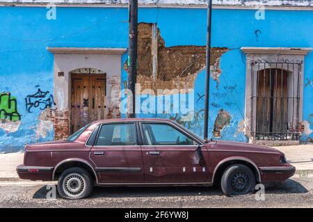 La vecchia macchina è rotta di fronte a un edificio colorato e malato façade nella città di Oaxaca in Messico Foto Stock