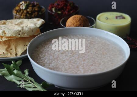 Porridge di riso o Kanji insieme al chutney di cocco, il toro di patate di barbabietola, moong fritto mescolato, papad fritto e latticello temperato. Un pasto preferito di Foto Stock