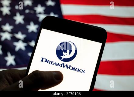 In questa illustrazione fotografica l'etichetta americana di produzione del film DreamWorks logo visto visualizzato su uno smartphone con una bandiera degli Stati Uniti sullo sfondo. Foto Stock