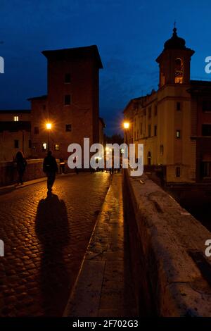 Un'ampia foto delle case e delle chiese di Tiberine Isola di Roma al tramonto contro un cielo blu scuro Foto Stock