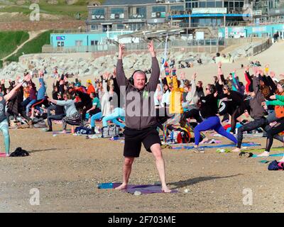 Newquay, Cornovaglia, Inghilterra, 3 aprile 2021. Tempo nel Regno Unito: Rinfrescati con il sole per una lezione di yoga di massa che coinvolge più di 300 partecipanti. Discoteca silenziosa yoga organizzato da Anthony Durkin DJ in combinazione con Oceanflow yoga. Spiaggia di Fistral. Credit: Robert Taylor/Alamy Live News Foto Stock