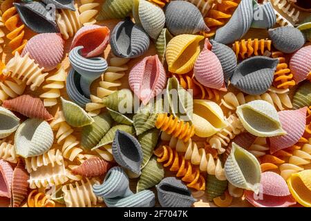 Diversi tipi di pasta secca colorata italiana come sfondo. Primo piano della macro. Foto Stock