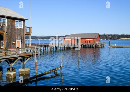 Edificio rosso sul molo di legno nel popolare turista Città di Coupéville nello stato di Washington sotto il cielo blu chiaro Con vista su Penn Cove Foto Stock