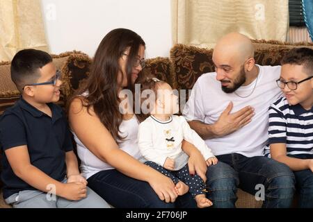 Felice famiglia ritratto madre e padre nel loro 30s, figli di 9 e 7 anni, e figlia infantile, età 7 mesi, padre che interagisce con bambina, gruppo Foto Stock