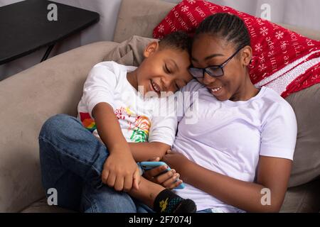 ragazza di 12 anni con il fratello di 7 anni guardando un gioco o un video sul telefono cellulare Foto Stock