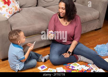 ragazzo di 3 anni con la madre, giocando con alfabeto e carte numeriche che hanno un pezzo di puzzle che si inserisce all'interno della carta di apprendimento a casa Foto Stock