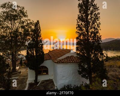 Vista aerea della chiesa di montagna Kastro e della città sull'isola di Poros durante il tramonto. Grecia in estate Foto Stock