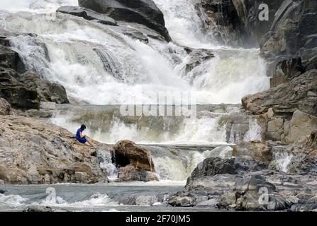 Turista seduto sulle rocce a Ba ho cascata, Nha Trang, Vietnam Foto Stock