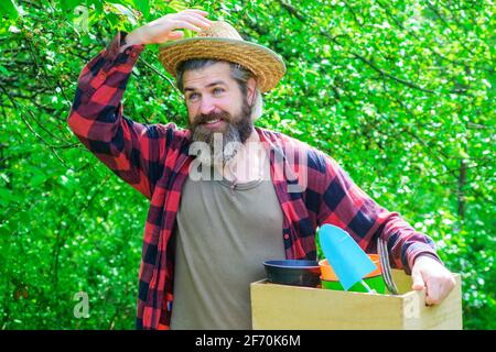 Molla. Uomo bearded con gli attrezzi di giardinaggio. Felice agricoltore in giardino di primavera. Giardiniere con attrezzi di giardinaggio Foto Stock